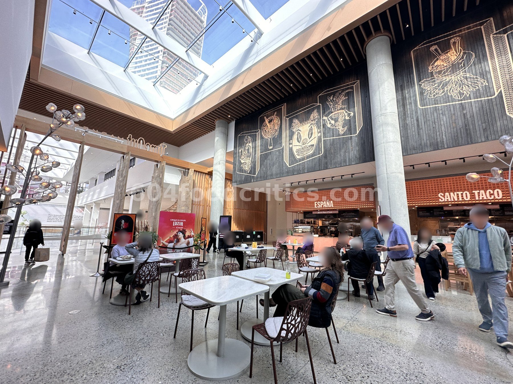 Shared seating at Time Out Market Vancouver with murals above the España and Santo Taco counters
