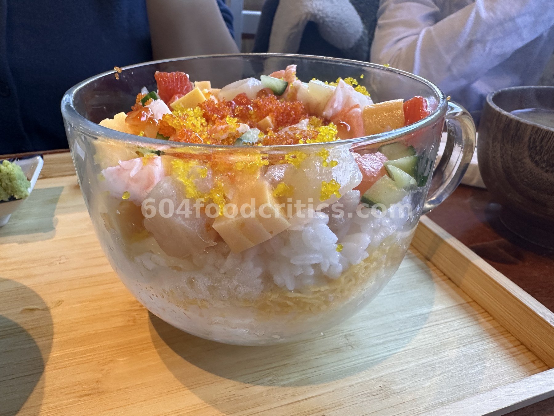 Seafood bara chirashi bowl in a glass mug with salmon roe, tuna, salmon, tamago and cucumber over sushi rice